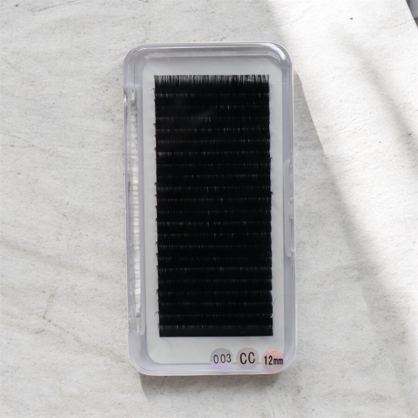 Box of false eyelashes on a textured white background