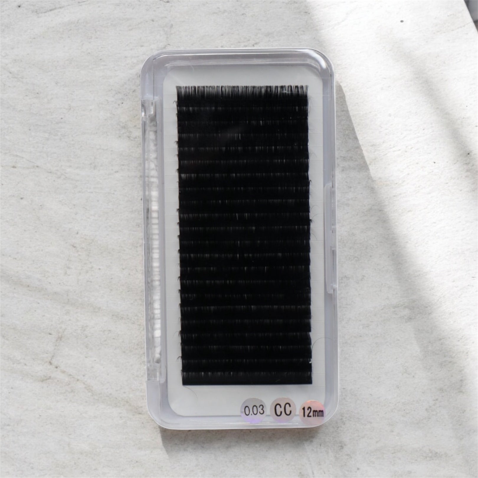 Box of false eyelashes on a textured white background